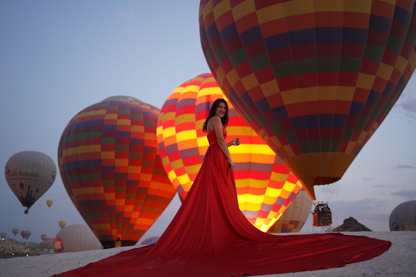 Our guest in a red dress with glowing balloons at dawn in Cappadocia