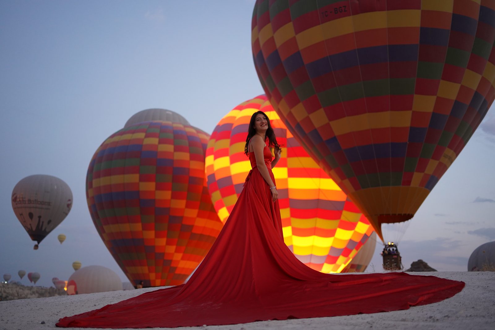Our guest in a red dress among glowing hot air balloons in Cappadocia